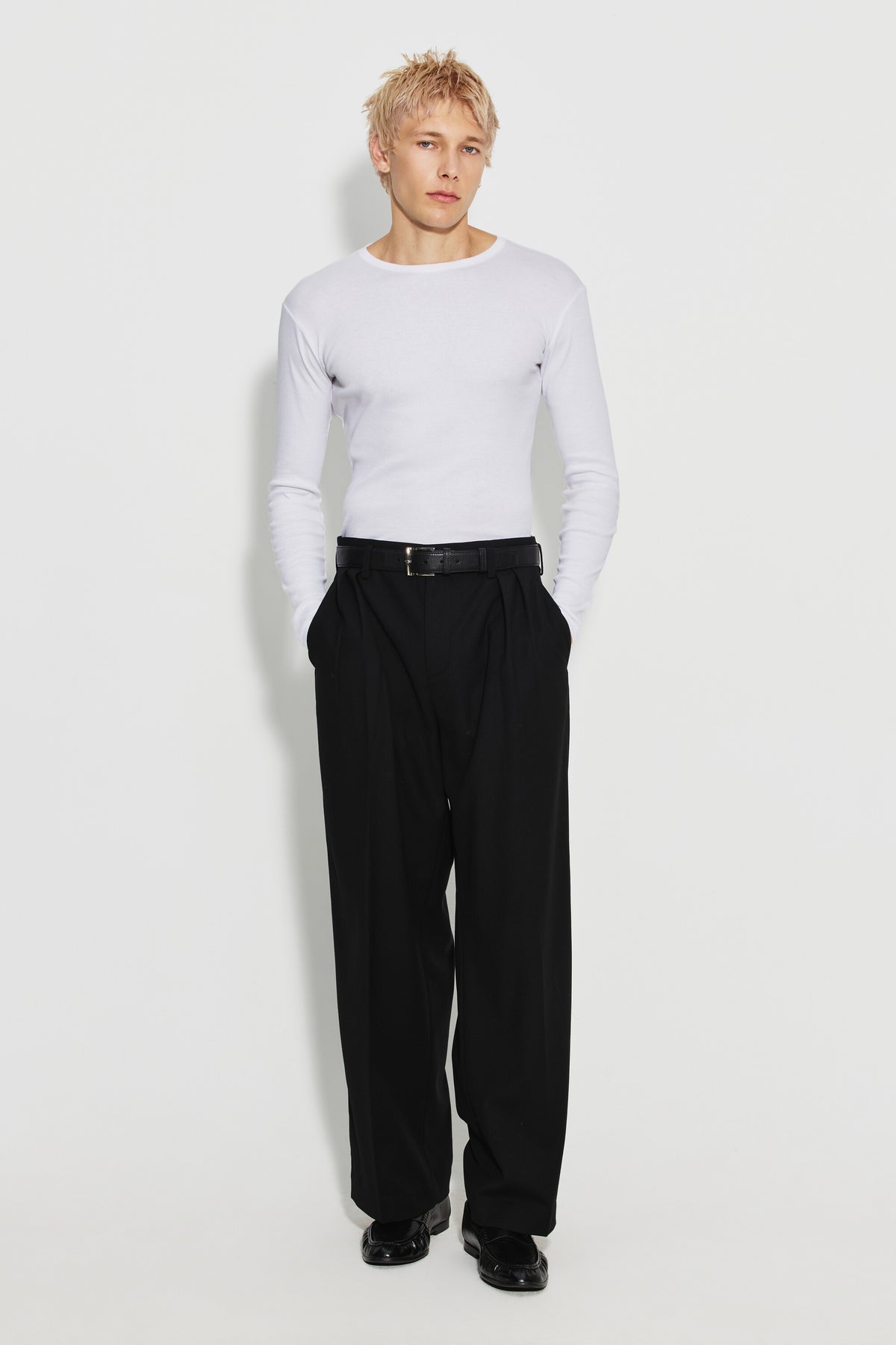 Maillot de corps homme blanc à manches longues en coton Pima, fabriqué à Roanne, porté avec un pantalon noir, vue en pied.
