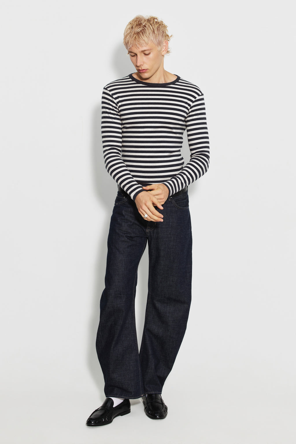 Maillot de corps homme noir et écru en coton bio côtelé à manches longues, porté avec un jean bleu, vue en pied.