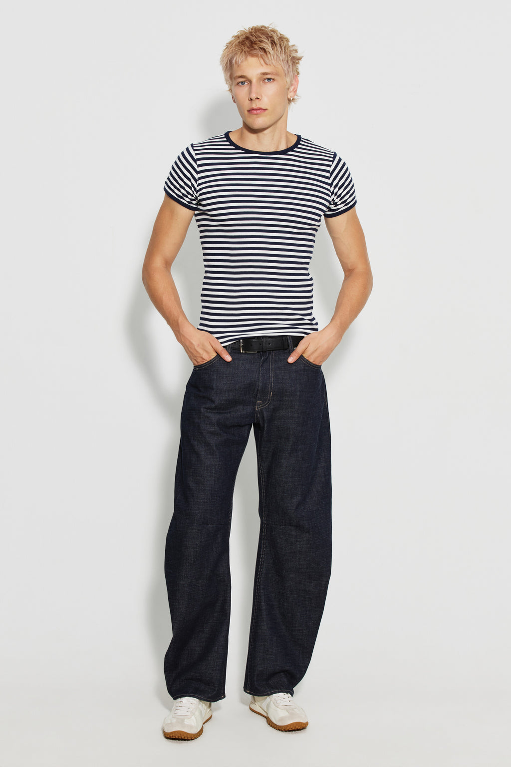 Maillot de corps homme bleu marine et écru en coton bio côtelé à manches courtes, porté avec un jean foncé et des baskets claires, vue de face en pied.