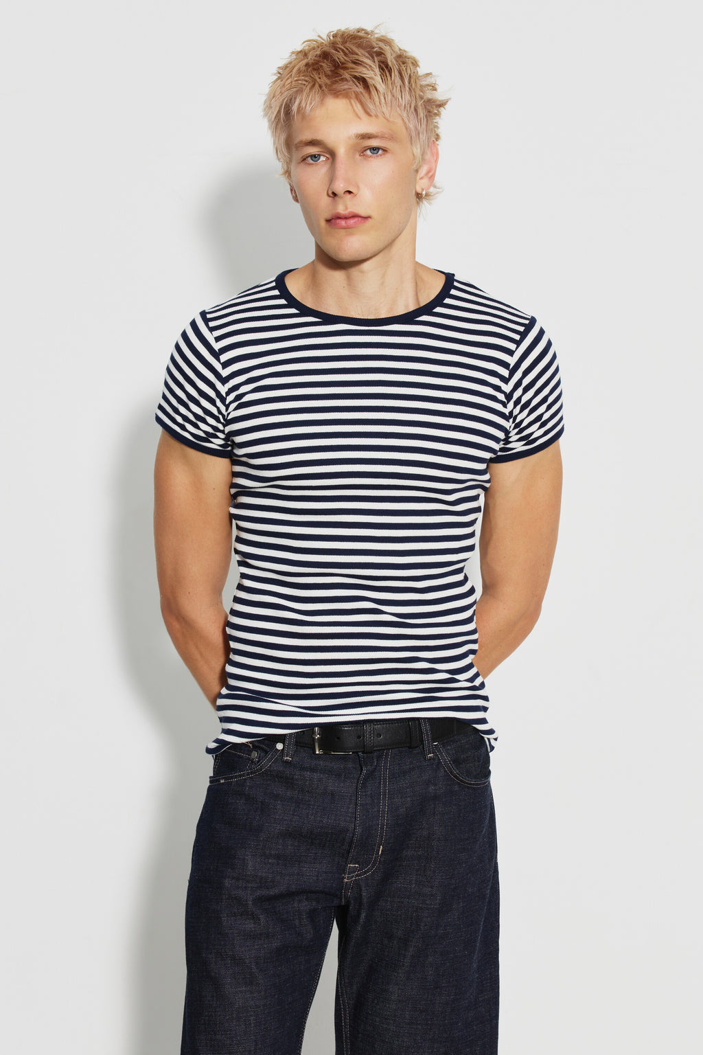 Maillot de corps homme bleu marine et écru en coton bio côtelé à manches courtes, porté de face avec un jean foncé, les mains derrière le dos. Made in France.