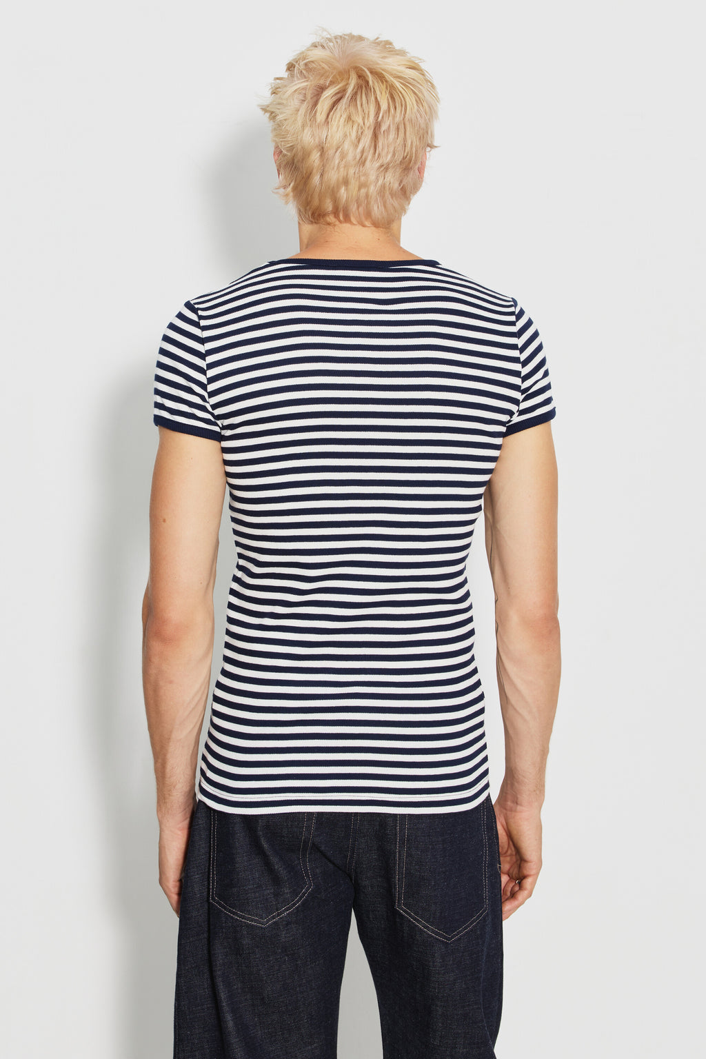 Maillot de corps homme bleu marine et écru en coton bio côtelé à manches courtes, porté de dos avec un jean foncé, vue des rayures et des manches.