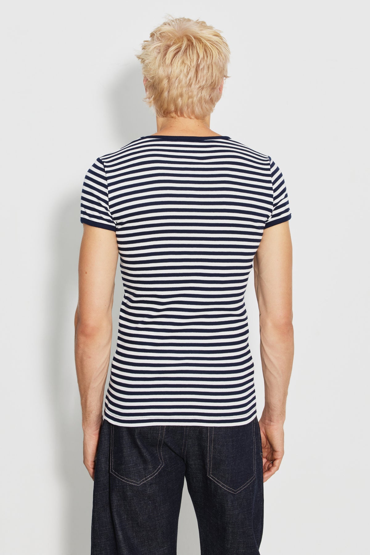 Maillot de corps homme bleu marine et écru en coton bio côtelé à manches courtes, porté de dos avec un jean foncé, vue des rayures et des manches.