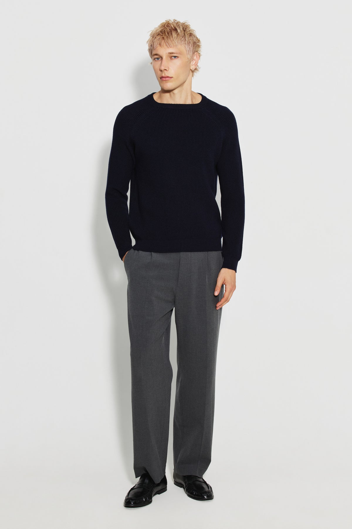 Pull homme bleu marine en laine mérinos à manches raglan, porté avec un pantalon gris et des chaussures noires, vue de face en pied.