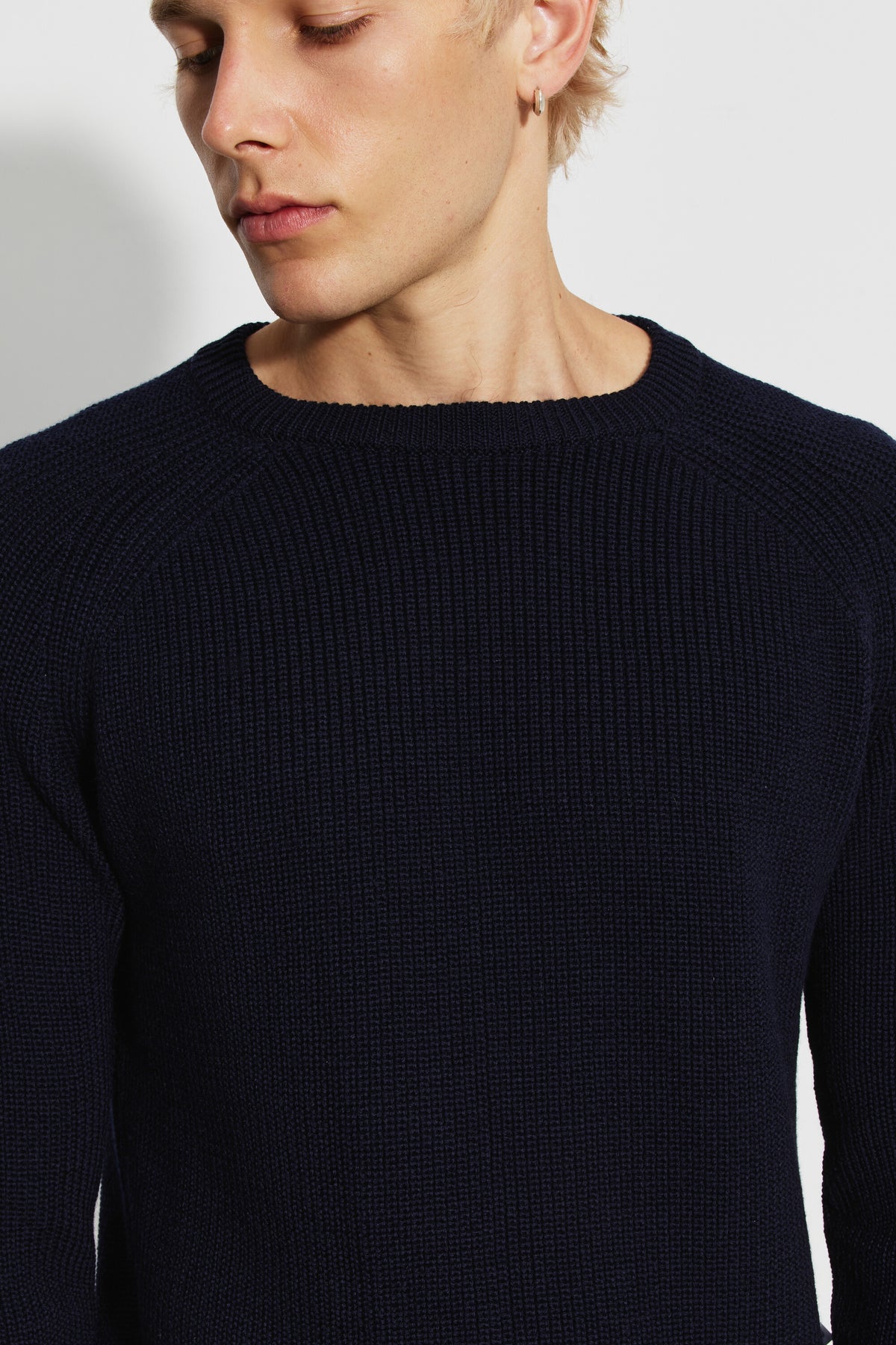 Pull homme bleu marine en laine mérinos à manches raglan, vue rapprochée du col rond, des manches raglan et de la maille perlée.