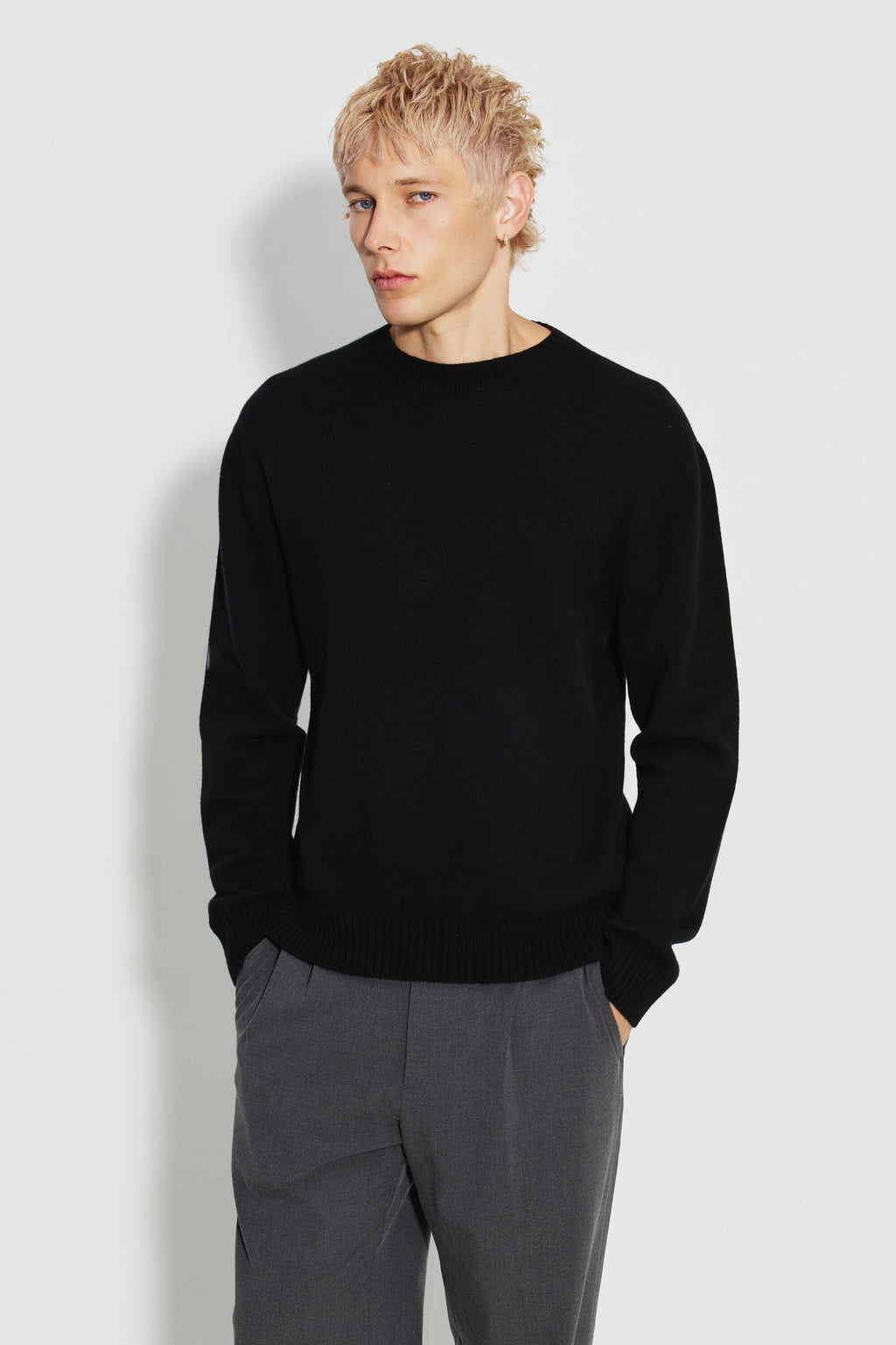 Pull mérinos et cachemire homme noir – vue de face avec un pantalon gris.