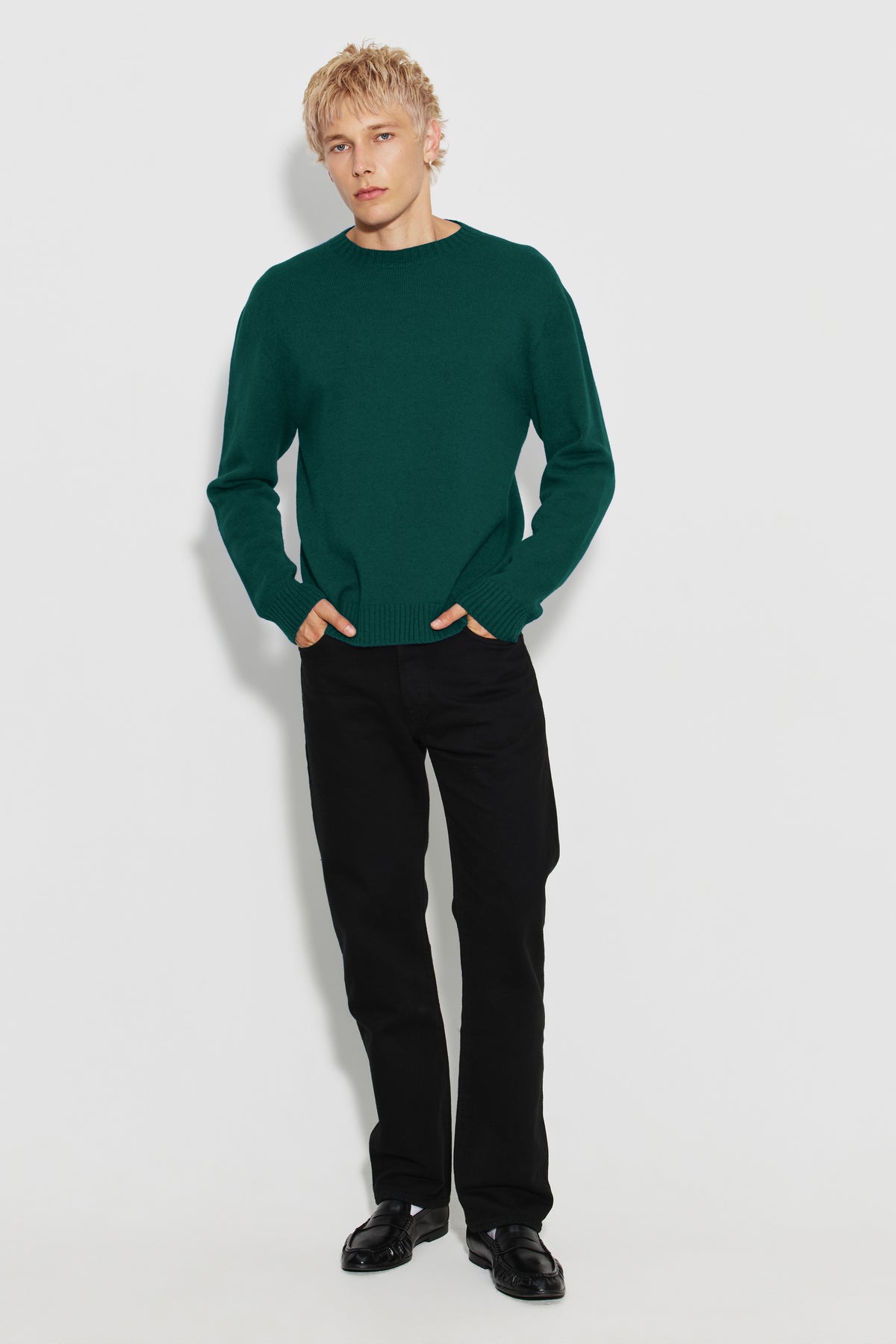 Pull homme vert en laine mérinos et cachemire, vue de face en pied avec un pantalon noir.
