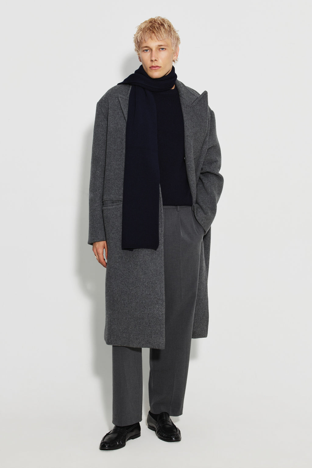 Écharpe homme bleu marine en laine mérinos, portée avec un manteau gris et un pantalon gris, vue de face en pied.