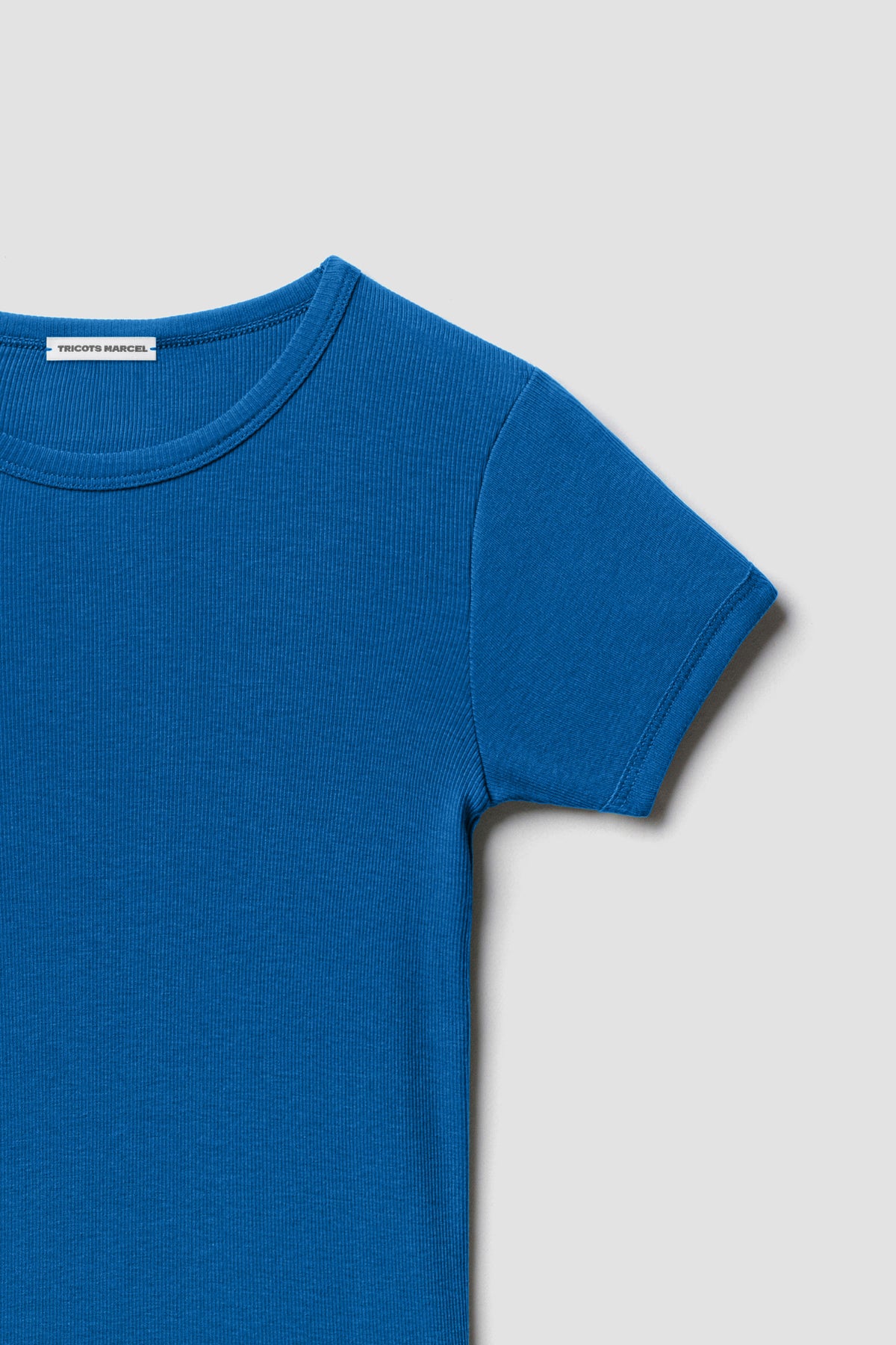Maillot de corps bleu à manches courtes en coton Pima côtelé, détail du col rond, de l’épaule et de la manche.