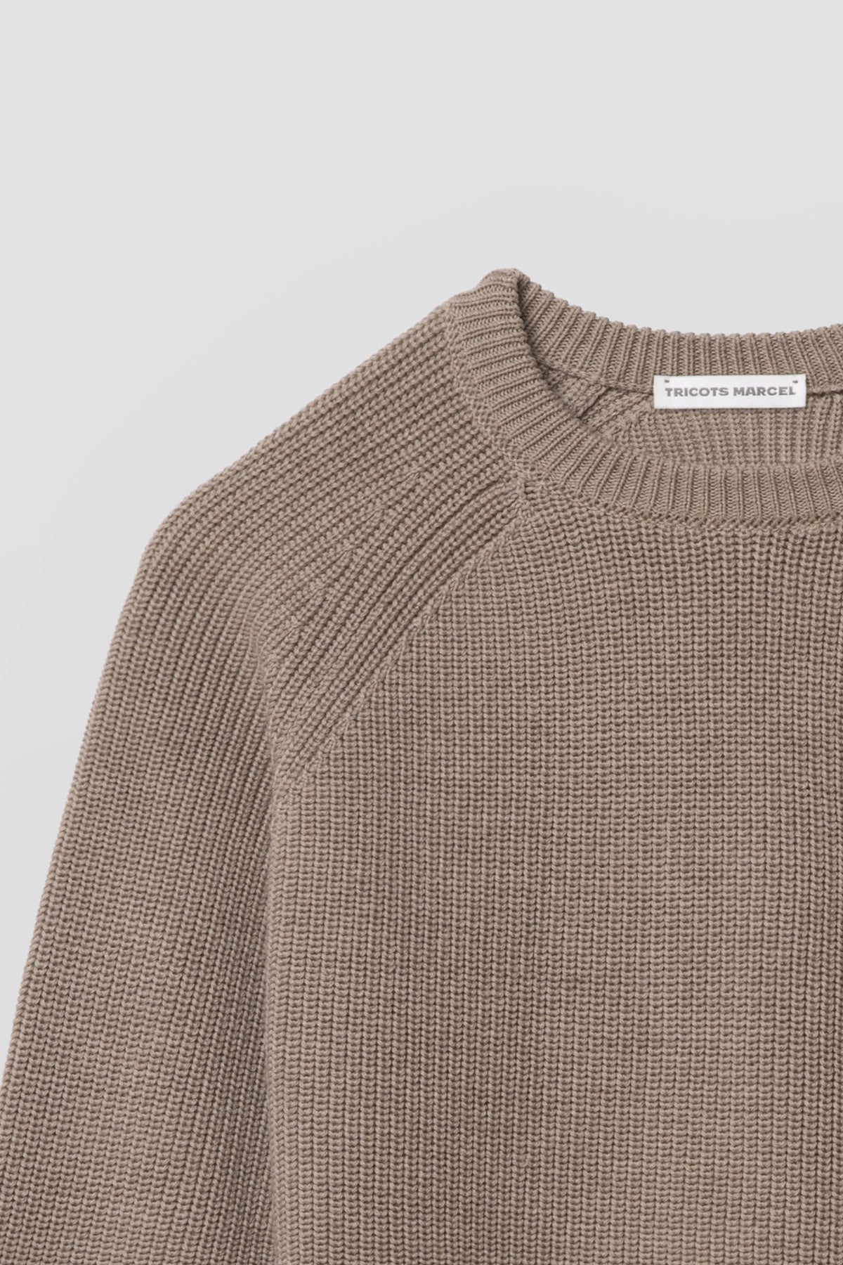 Pull homme et femme beige en laine mérinos à manches raglan, détail du col rond, de l’épaule raglan et de la maille perlée. Made in France.