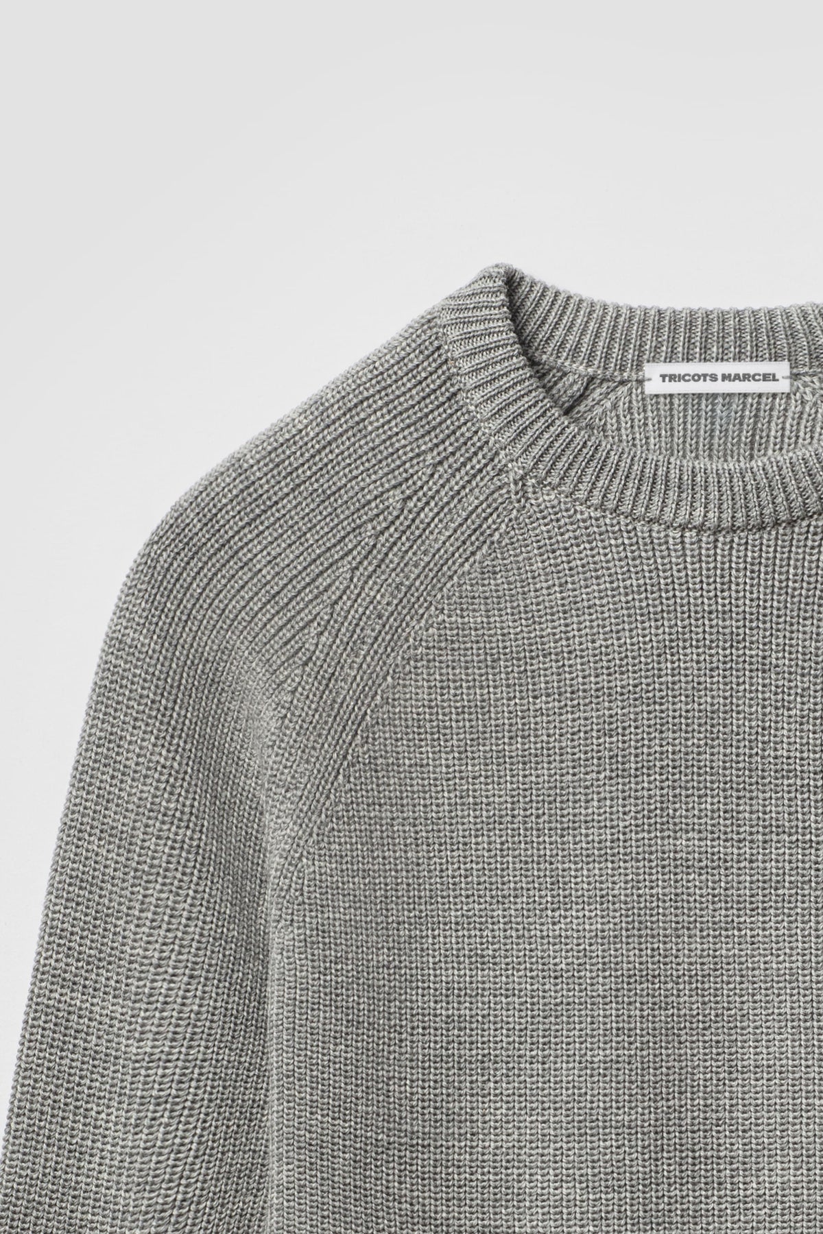 Pull gris en laine mérinos à manches raglan, détail du col rond, de l’épaule raglan et de la maille perlée.