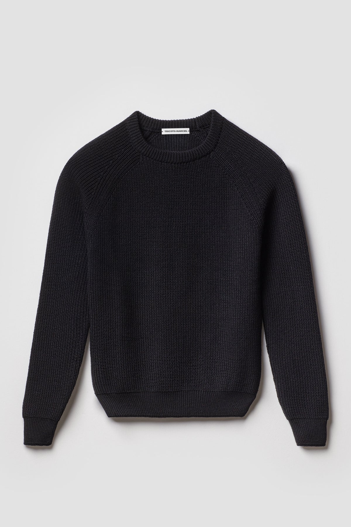 Pull homme et femme noir en laine mérinos à manches raglan, packshot de face montrant le col rond et la maille perlée.