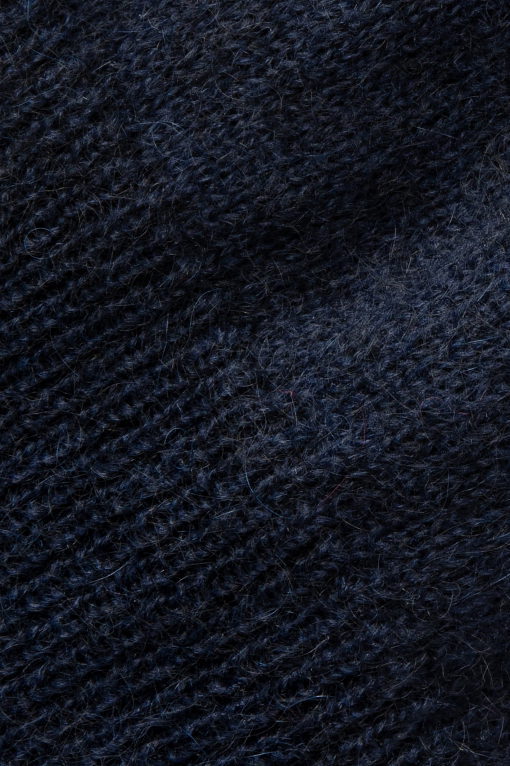 Pull bleu marine en mohair sans manches, gros plan sur la maille duveteuse.