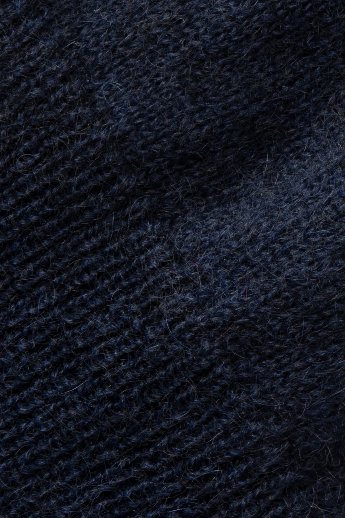Pull bleu marine en mohair sans manches, gros plan sur la maille duveteuse.