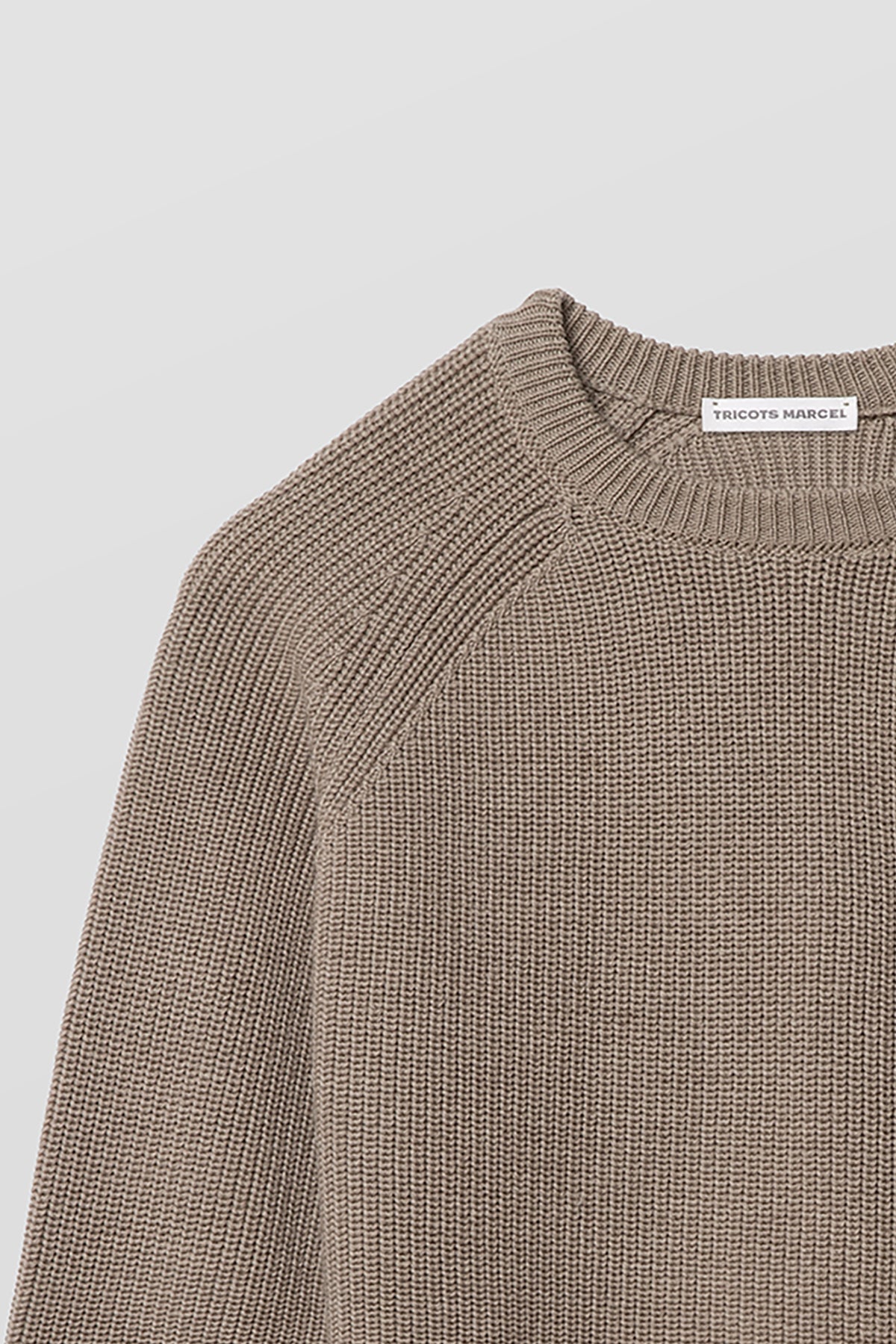 Pull homme et femme beige en laine mérinos à manches raglan, détail du col rond, de l’épaule raglan et de la maille perlée. Made in France.